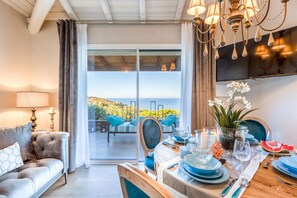A dining area with a table set for two, a sofa, and a view of the outdoors. - Villa in Sardinia Near Porto Ottiolu Beach (Budoni)