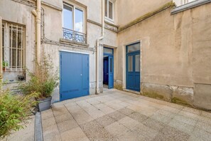 Ein Innenhof mit einer blauen Tür, einem Blumentopf und einem Steinboden.