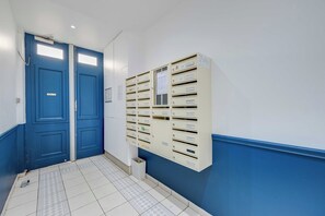 Ein Flur mit blauen Türen, ein Postraum mit beschrifteten Schubladen und ein Fliesenboden.