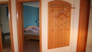 A bedroom with a bed, a wooden door with a hanger, and a blue wall. - Ferienwohnung in Orth auf Fehmarn (Orth)