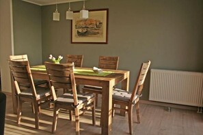Un comedor con una mesa y sillas de madera, un cuadro en la pared y un radiador debajo.