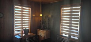 Ein Zimmer mit Holzwänden, einem Holztisch mit Blumentopf, einem kleinen Schrank und einer Wandleuchte.