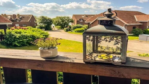 Zona residencial con casas, una terraza de madera, un farol y una planta en maceta.