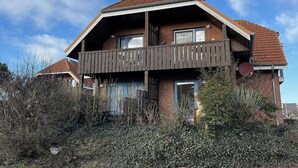 Uma casa de dois andares com varanda, fachada de tijolos e telhado telhado.