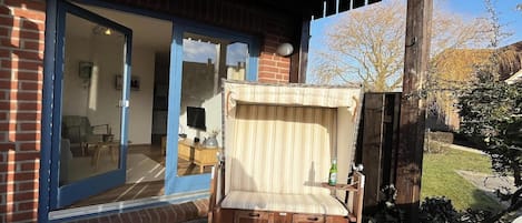 A wooden bench with storage drawers, a glass door entrance, and a brick exterior.