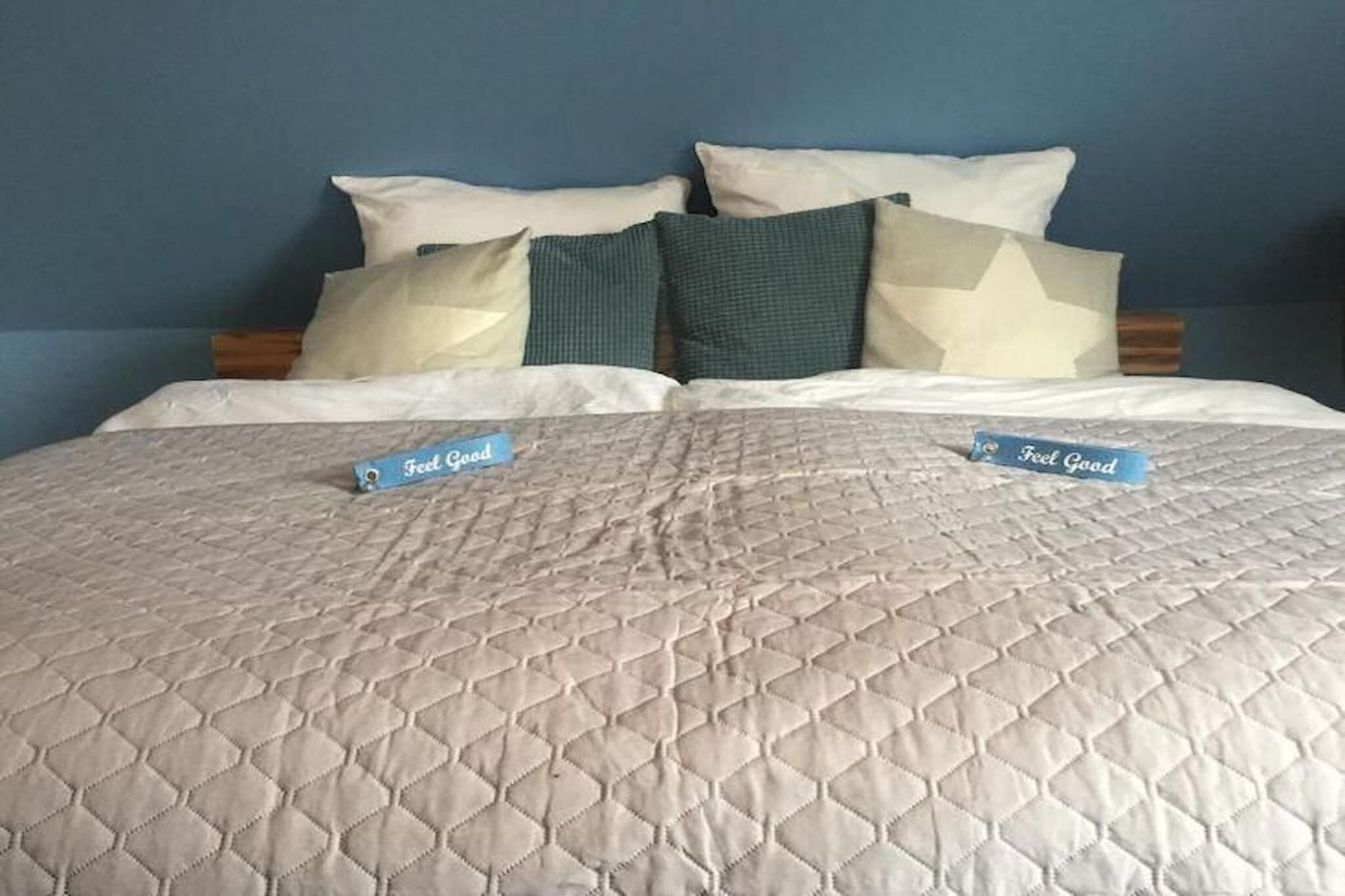 Una cama con cubrecolcha acolchada y dos almohadas, cada una con una etiqueta que dice 'Feel Good'.