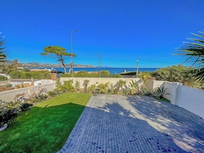 Een terras op het dak met uitzicht op zee, een betegeld terras en diverse planten.