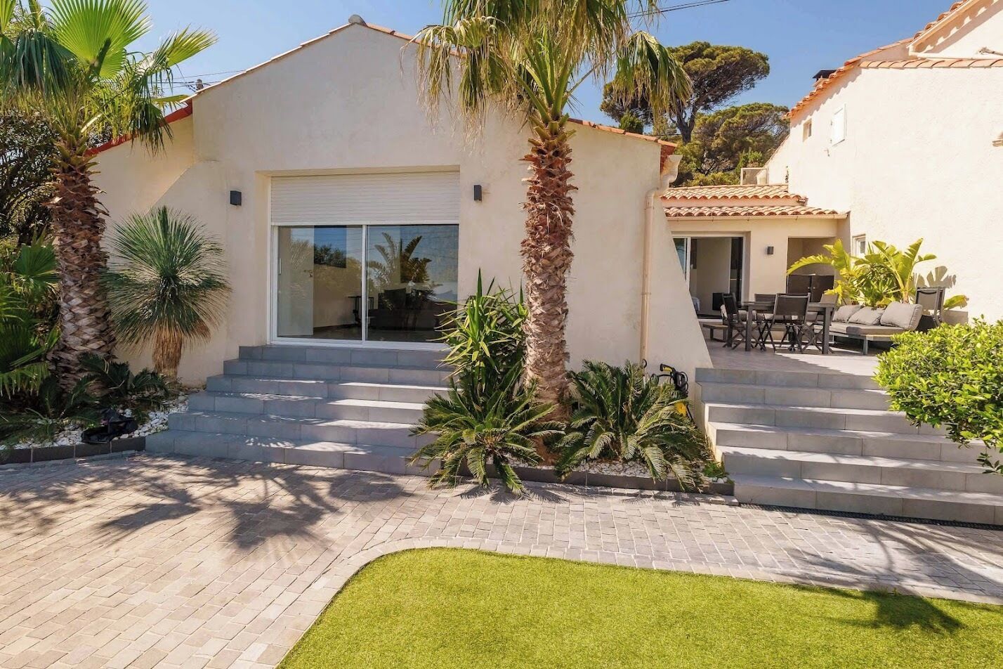 A modern house with a garage, a patio with outdoor furniture, and a well-maintained lawn.