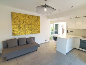 Een modern interieur met een bank, een keuken en een groot, geel kunstwerk aan de muur.