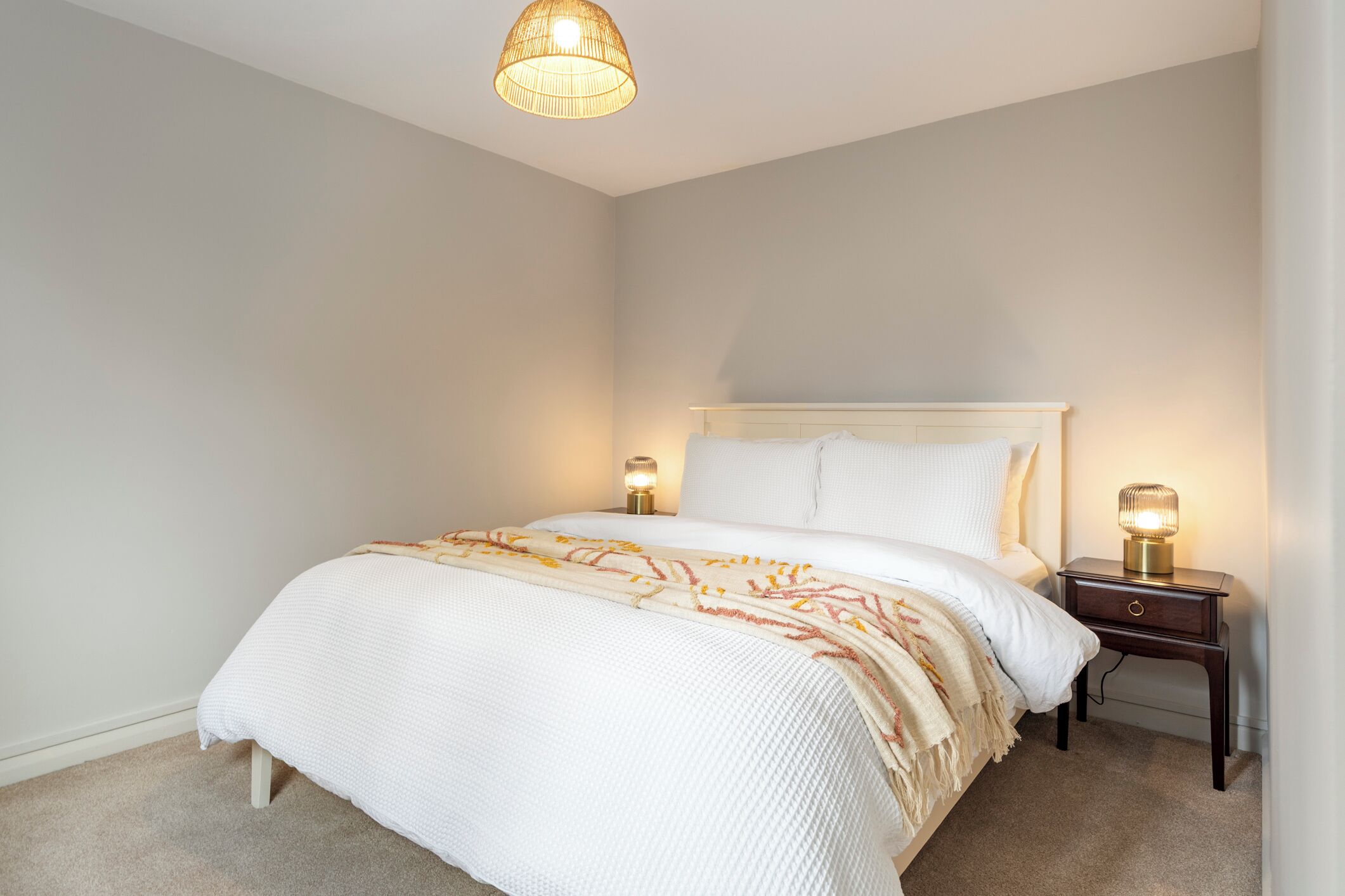 Una camera da letto con un letto, lampade sui comodini, un lampadario e un pavimento tappezzato.