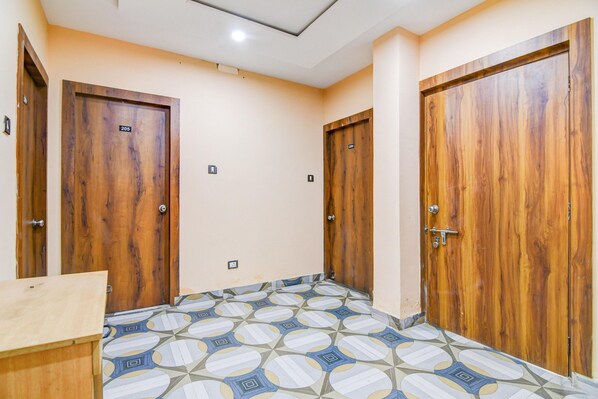 A hallway with three wooden doors, a patterned floor, and a light-colored wall.