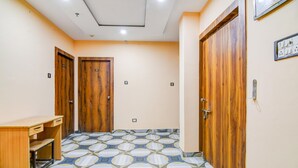 A hallway with wooden doors, a desk, and patterned floor tiles. - Super Deluxe Room More Bimla Regency (Barakpur)