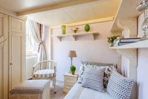 A bedroom with a bed, bedside tables, a chair, a window with curtains, and shelves with decorative items. - Apartment in Lucca Near Guinigi Tower (Lucca)