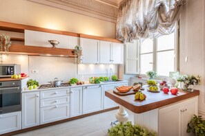A kitchen with white cabinets, a wooden countertop, a stove, and various fruits and vegetables. - Apartment in Lucca Near Guinigi Tower (Lucca)