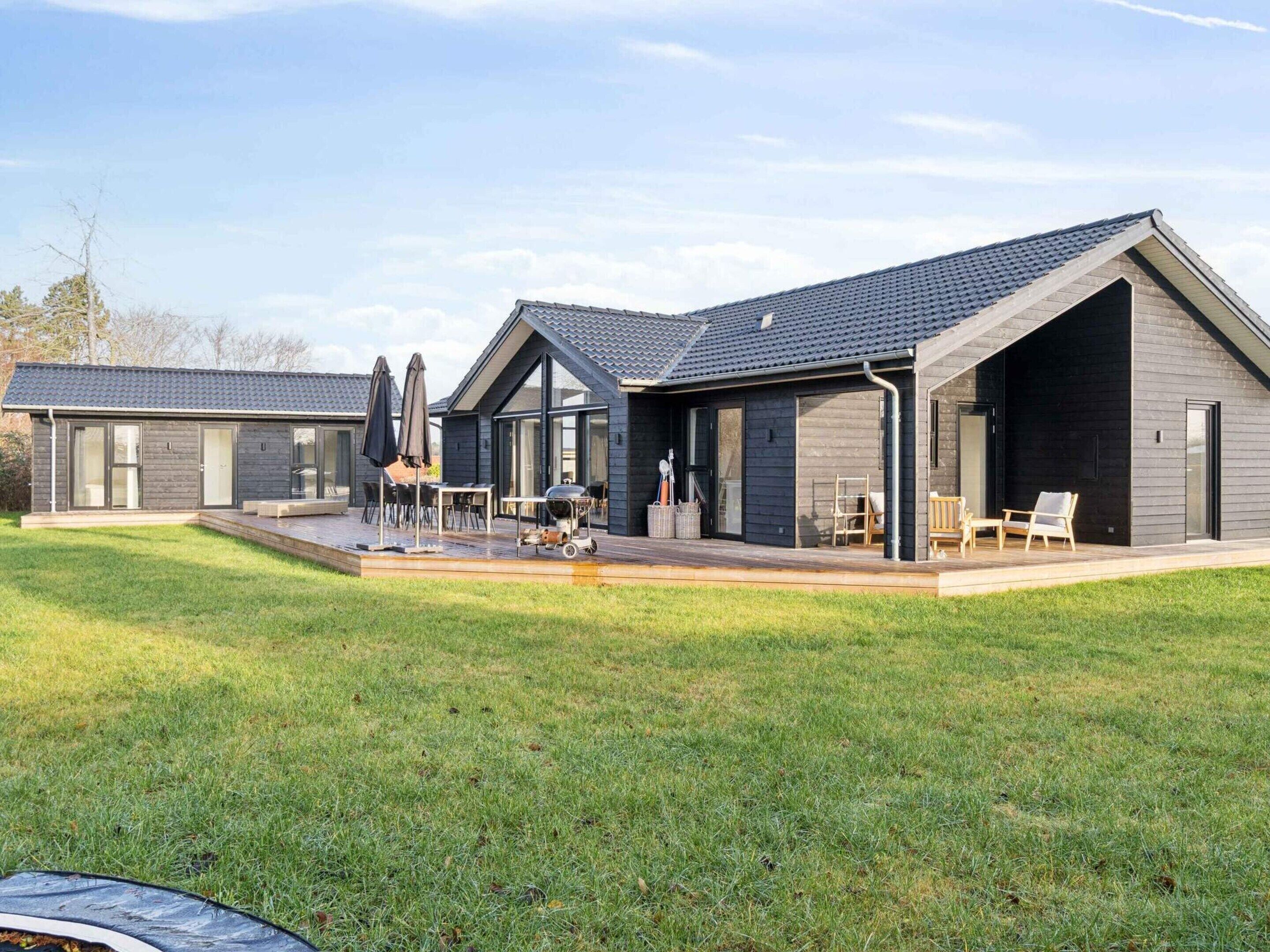 Una casa moderna con un patio, mobiliario exterior y una zona de barbacoa.