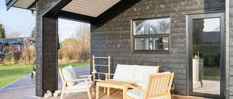 A wooden deck with outdoor furniture, a covered patio, and a sliding glass door.