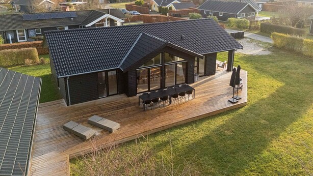 A modern house with a large deck, a covered patio, and a view of a residential area. - 4 Star Holiday Home in Rude (Bisserup)