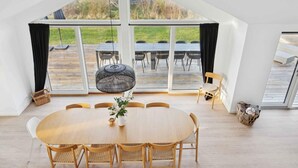 A spacious room with a large table, chairs, and a hanging light fixture. - 4 Star Holiday Home in Rude (Bisserup)