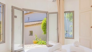 Une chambre à coucher avec un lit, une fenêtre et une porte donnant sur un espace extérieur.