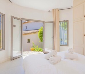 Ein Schlafzimmer mit einem Bett, einem Fenster und einer Tür, die zu einem Außenbereich führt.