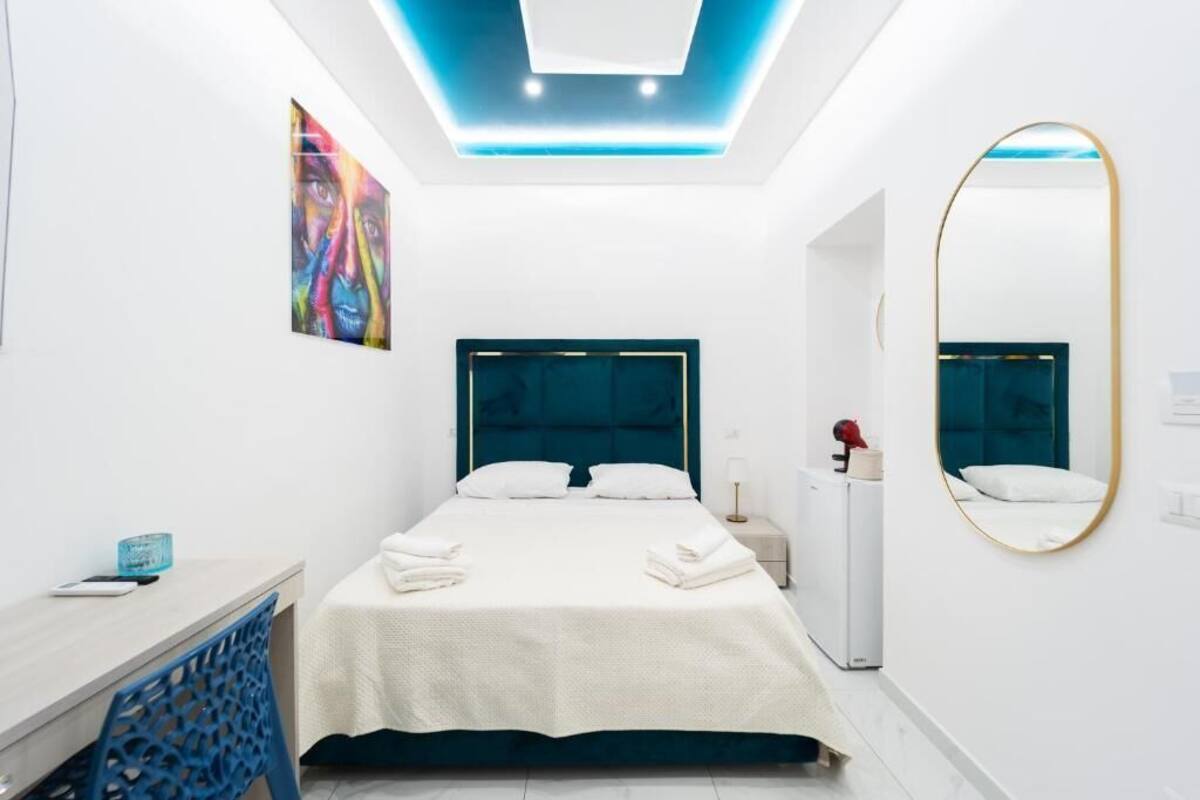 Quarto de hotel moderno com uma cama, mesa de cabeceira e um espelho.