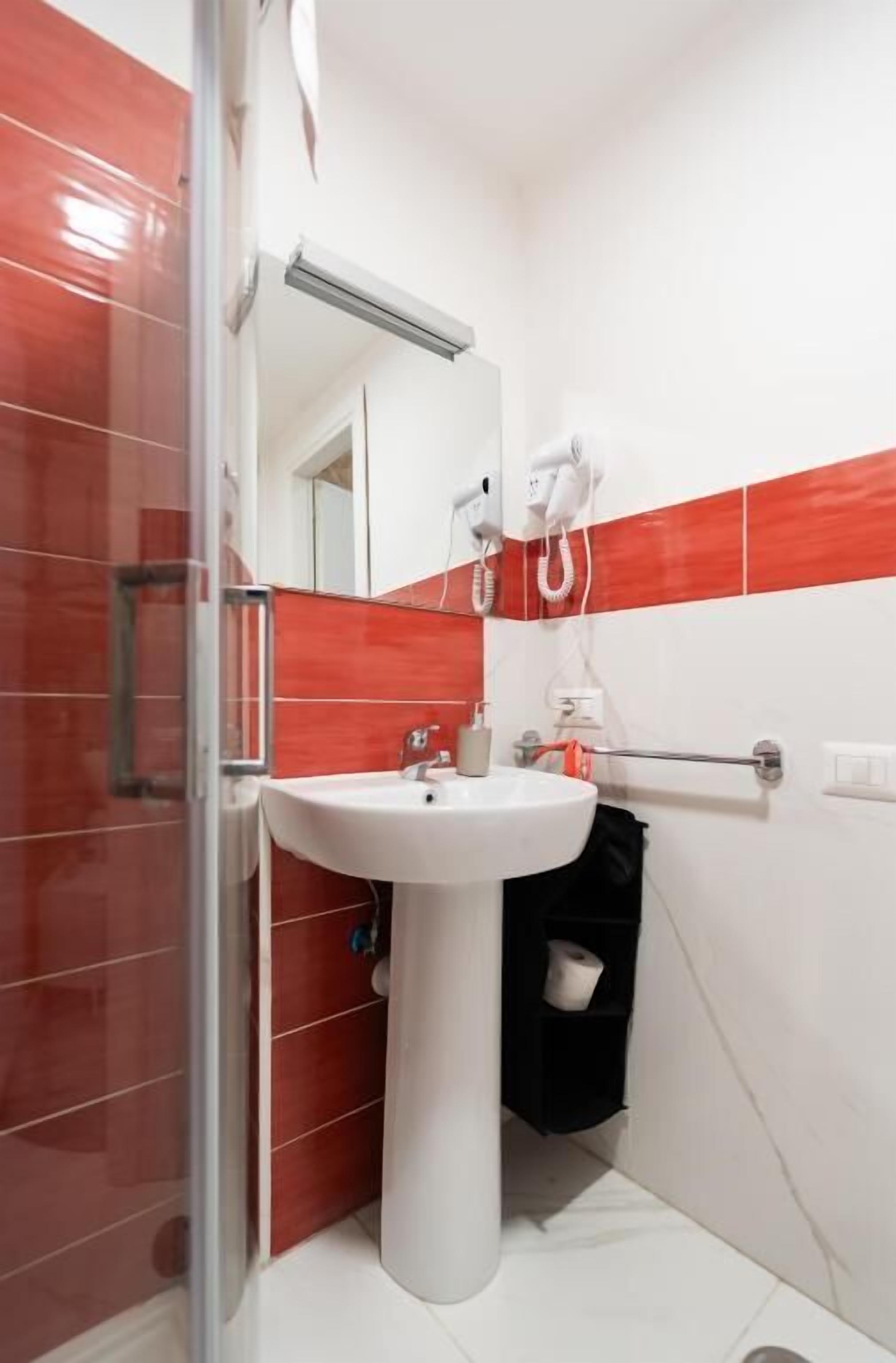 A bathroom with a glass shower enclosure, a white sink, and a towel rack.