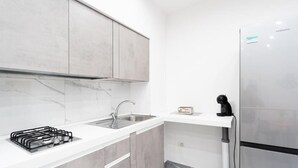 A modern kitchen with a stainless steel refrigerator, a gas stove, and a sink. - Vico Teresa 148 (Naples)