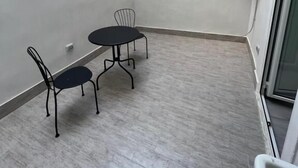 A small, enclosed patio area with a tiled floor, a table with two chairs, and a small window. - Vico Teresa 148 (Naples)