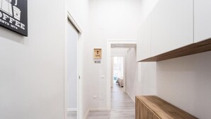 A hallway with a wooden bench, a sign with a key symbol, and a coffee shop sign on the wall. - Vico Teresa 148 (Naples)