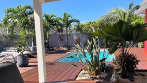 Un espace extérieur abrité comprenant une piscine, une terrasse en bois et des sièges.