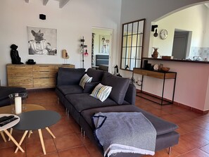 A modern living room with a sofa, a coffee table, a dining area with a kitchen counter, and a large mirror. - Villa PISCINE JACUZZI. 6 People 3 Bedrooms 3 SD (Saint-François)