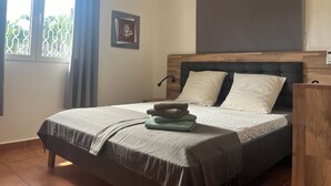 Une chambre à coucher avec un lit, une fenêtre avec des rideaux, un tableau encadré et une tête de lit.