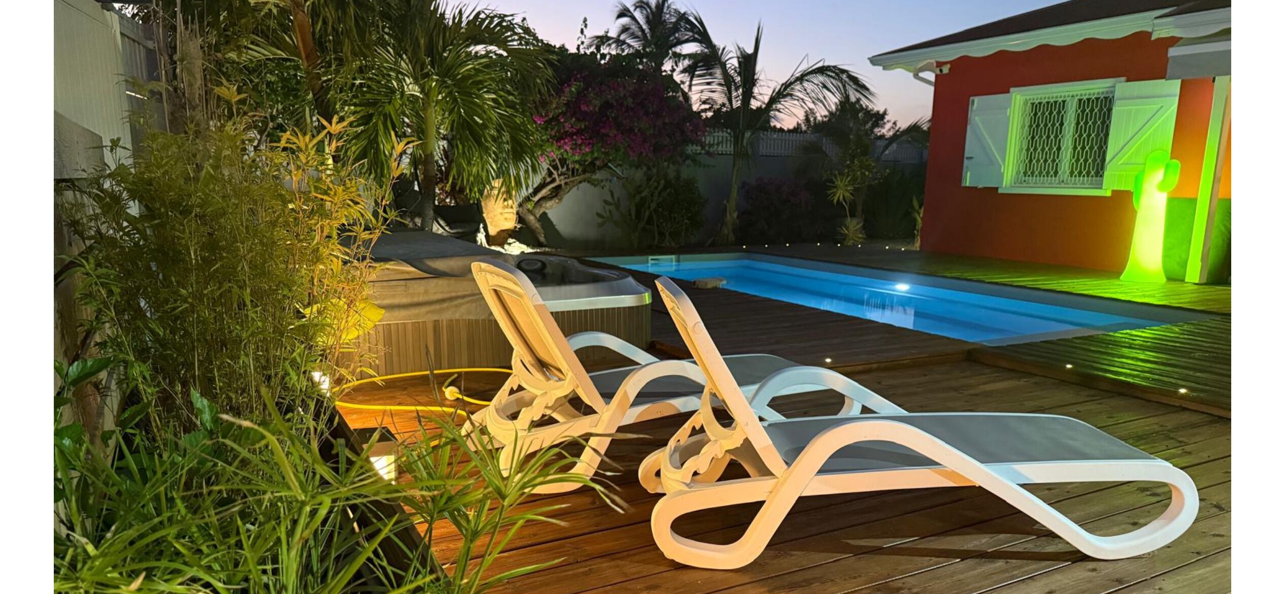 Un espace aménagé au bord de la piscine, avec des chaises longues, une terrasse en bois et une piscine.