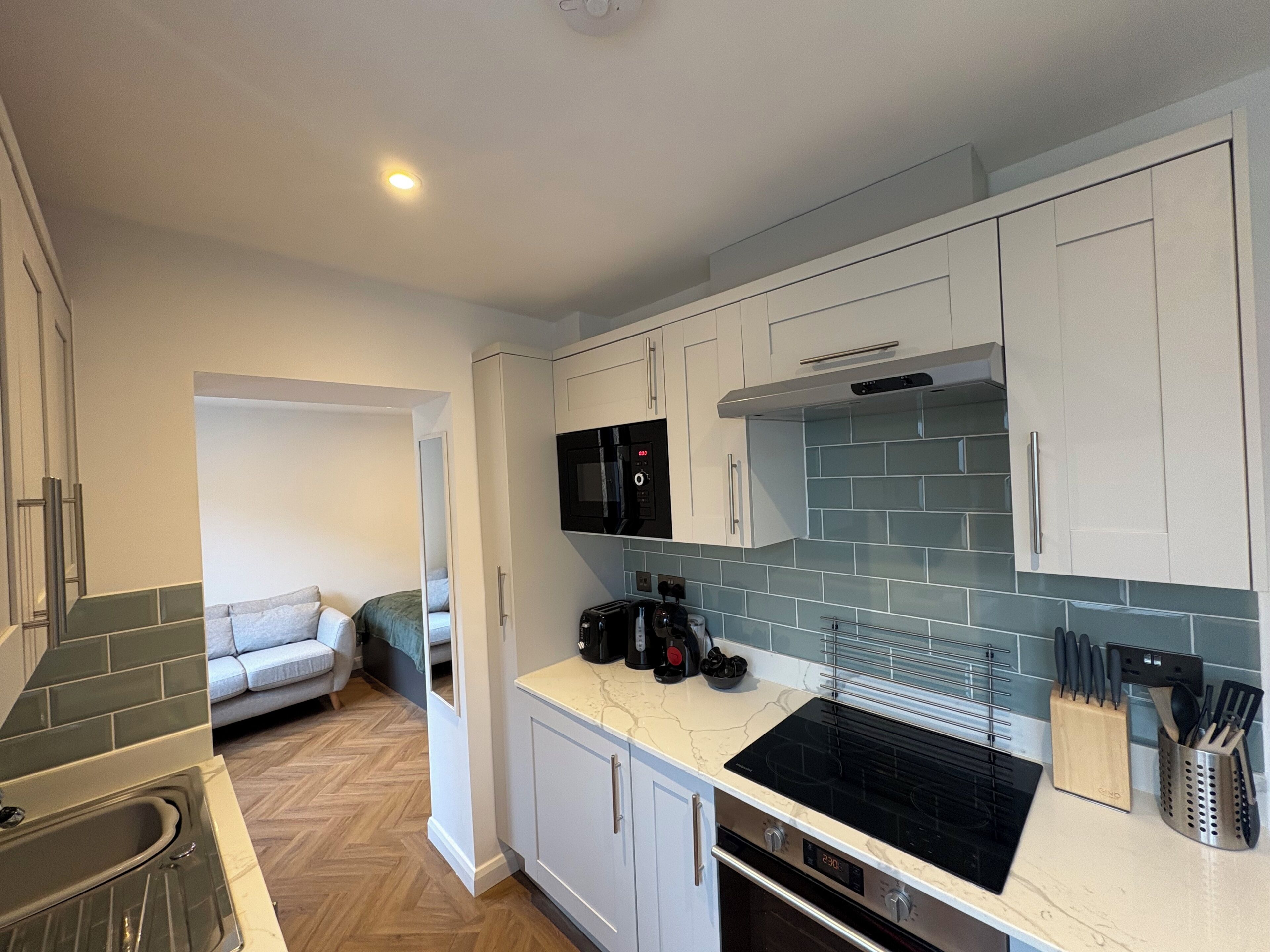 A modern kitchen with white cabinets, a black stove, and a tiled backsplash.