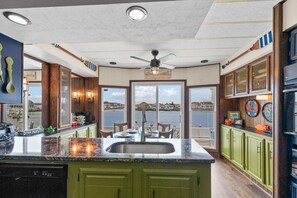 A kitchen with a large island, a view of the water, and a ceiling fan. - Lola B's Bayside Bungalow by Seaside Vacations & Sales (Ocean City)