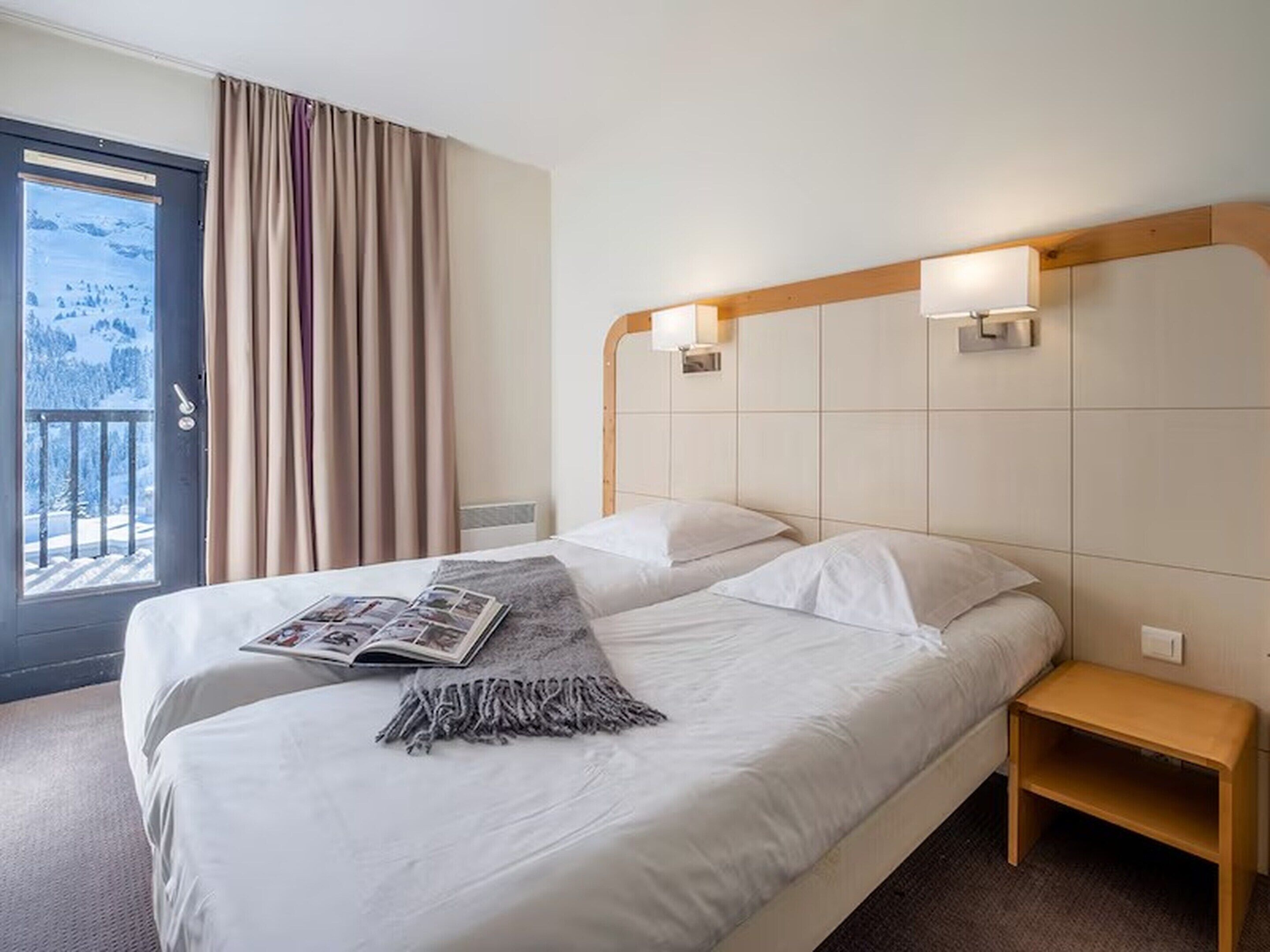 Une chambre d’hôtel avec un lit, une table de chevet et une fenêtre avec des rideaux.