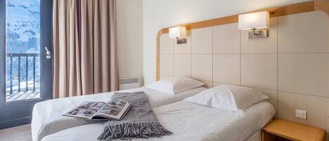 Une chambre d’hôtel avec un lit, une table de chevet et une fenêtre avec des rideaux.