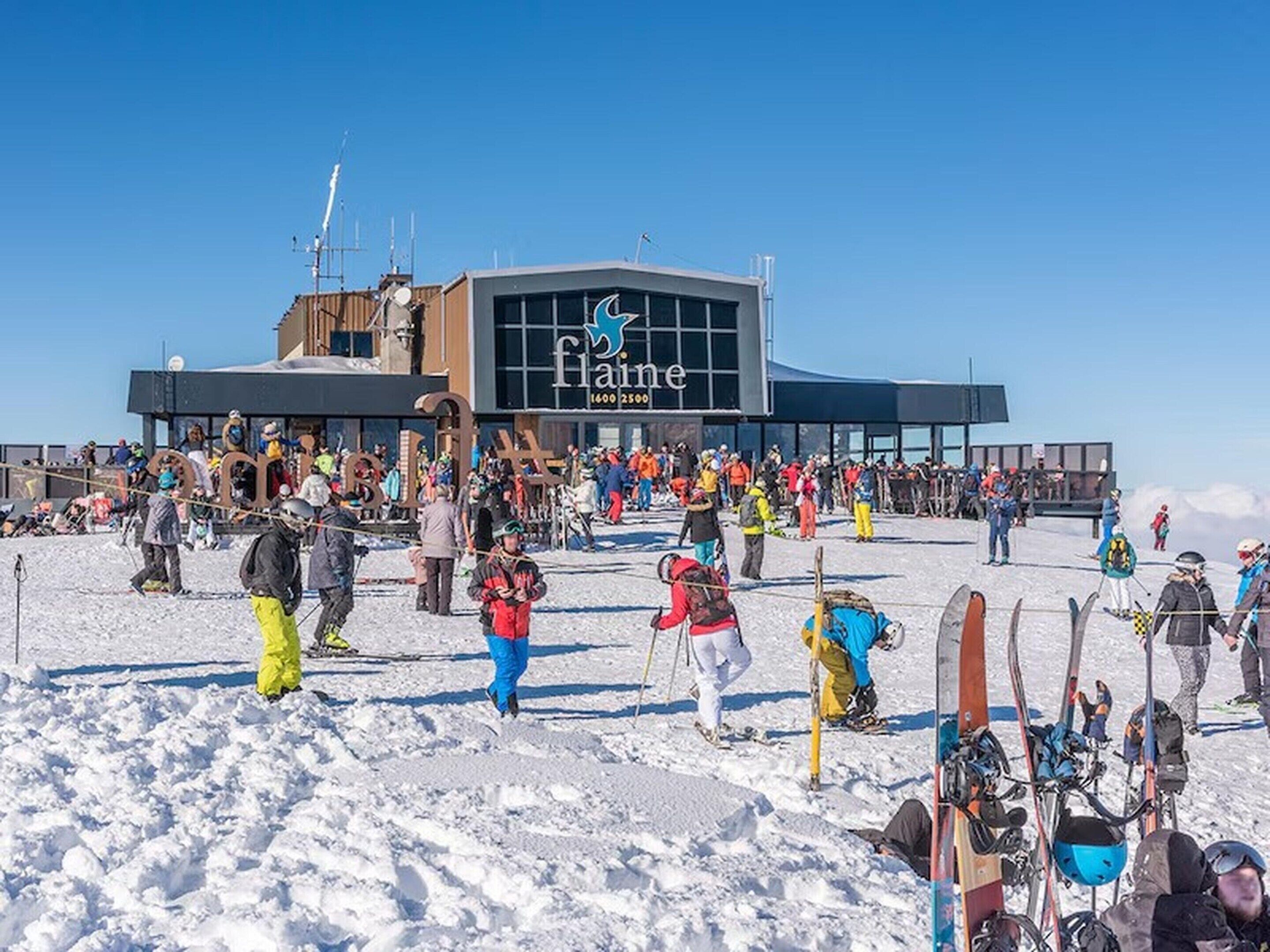 A ski resort with a large building labeled 'Faine' and a crowd of people in the foreground.