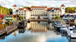 A waterfront hotel with a central building, a dock, and several boats. - 3 Person Holiday Park Home in Grosszerlang (Rheinsberg)