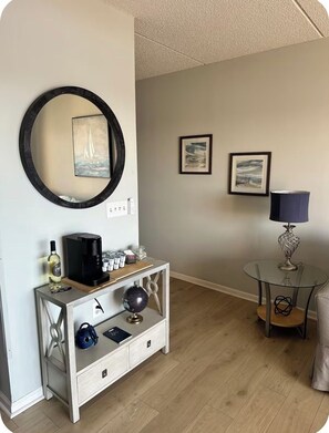 Ein Zimmer mit einem runden Spiegel, einer Kaffeemaschine, einem Globus und einem kleinen Tisch mit einer Lampe.