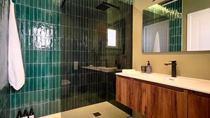 Une salle de bain moderne avec une douche à parois de verre, un meuble-lavabo en bois et un grand miroir.