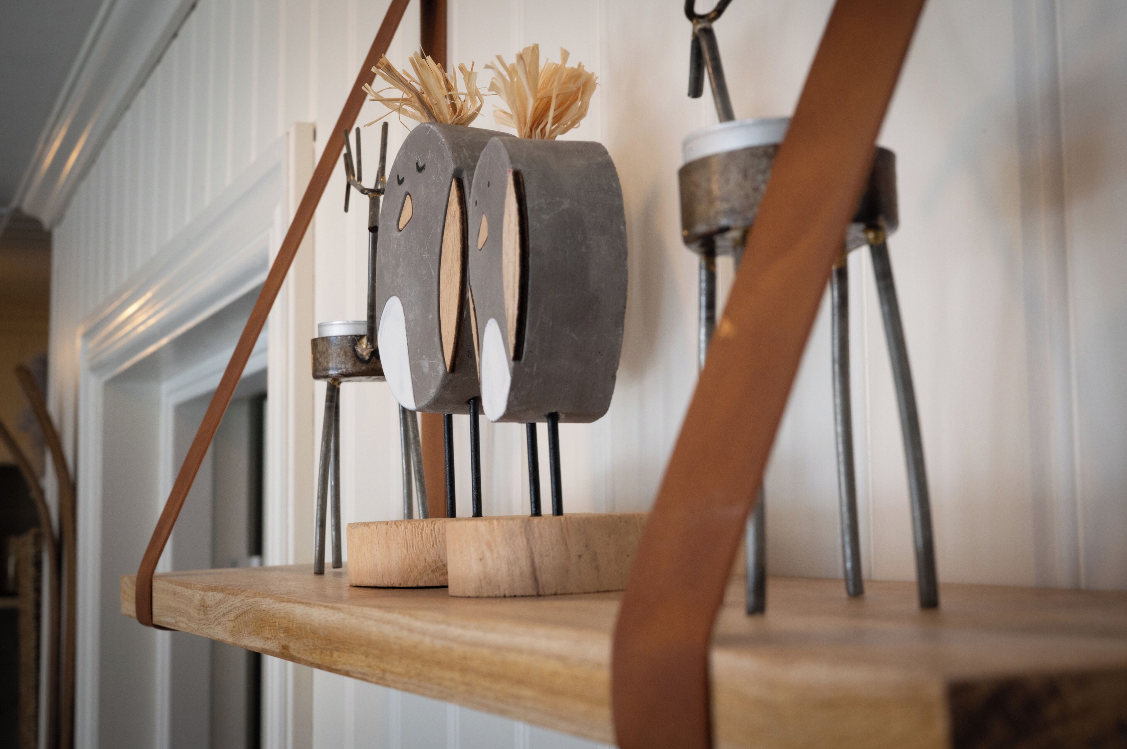 A wooden shelf with a rustic metal sculpture and a small metal pot.