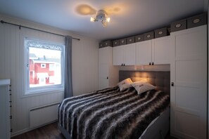 Un dormitorio con cama, ventana con cortinas, lámpara de techo e incluso armarios empotrados.