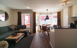 A cozy living room with a sofa, coffee table, and a dining area with chairs and a table.
