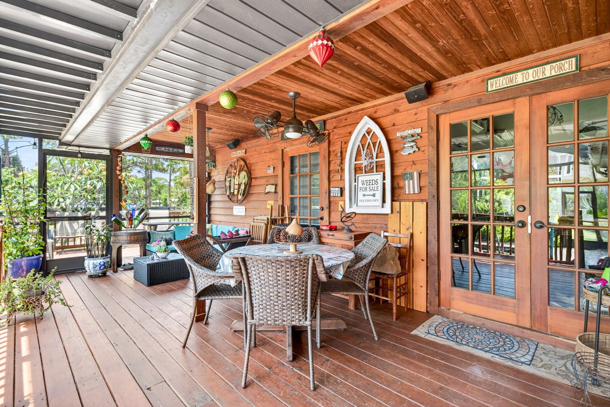 A wooden porch with wicker furniture, a table, and a 'WELCOME TO OUR PORCH' sign.
