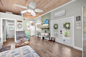 A spacious living room with a ceiling fan, a dining area with a table and chairs, and a kitchen area with a refrigerator and sink. - Adorable Estero Cottage - Heated Pool/Spa - Sauna (Estero)