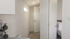 A narrow hallway with a door leading to a bedroom, a small window, and a table with a kettle. - Standard Caravan at Three Lochs Holiday Park (Newton Stewart)