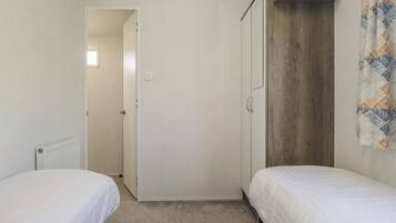 A small, single-bedroom room with a bed, a wardrobe, and a radiator.