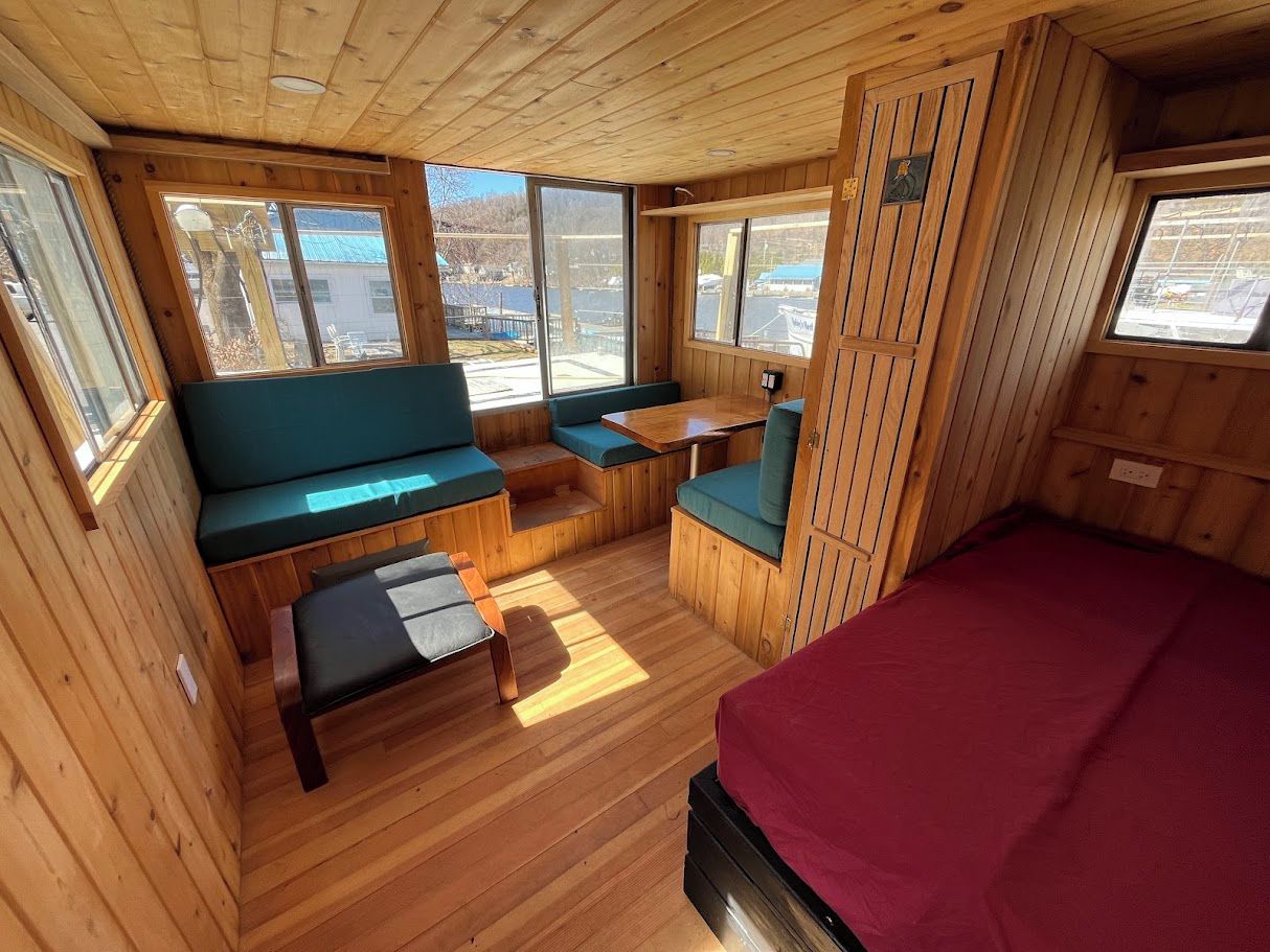 Een chaletinterieur met een bed, zithoek en ramen.