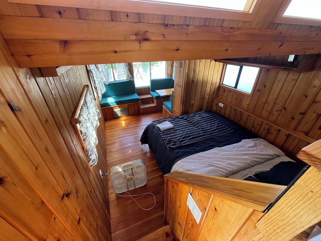 Ein Ferienhaus-Innenraum mit Bett, Sitzecke und Ventilator.